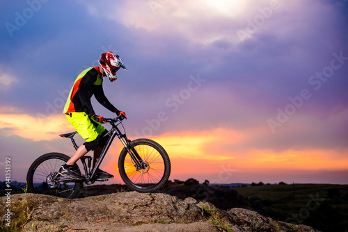 Professional Cyclist Riding the Bike on the Rock at Sunset. Extreme Sport Concept. Space for Text.