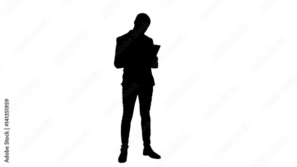 Silhouette Serious young manager standing and reading documents Silhouette Serious young manager standing and reading documents