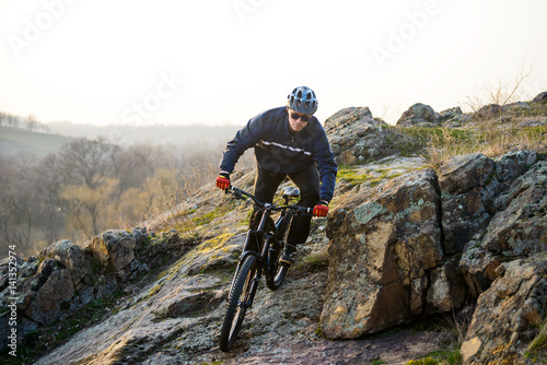 Enduro Cyclist Riding the Mountain Bike Down Beautiful Rocky Trail. Extreme Sport Concept. Space for Text.