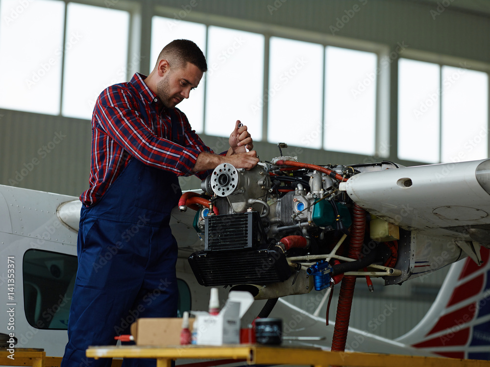 Technical worker repairing motor of jet before flight season
