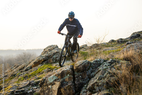 Enduro Cyclist Riding the Mountain Bike Down Beautiful Rocky Trail. Extreme Sport Concept. Space for Text.