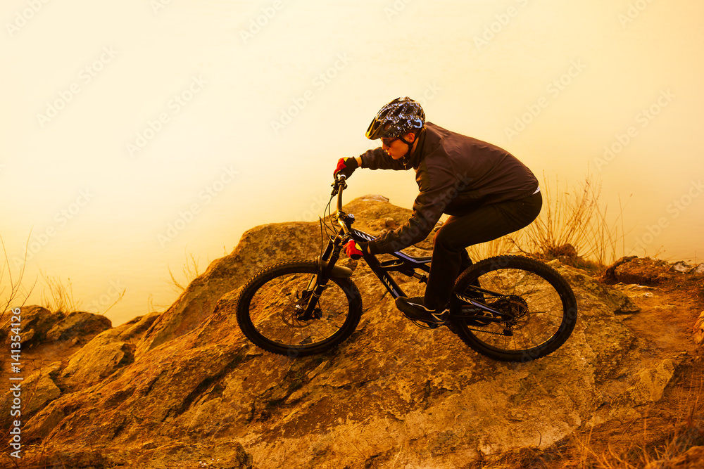 Obraz premium Enduro Cyclist Riding the Mountain Bike on the Rock. Extreme Sport Concept. Space for Text.