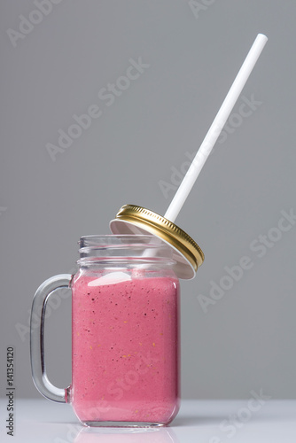 Jar tumbler mug with pink smoothie drink on table photo