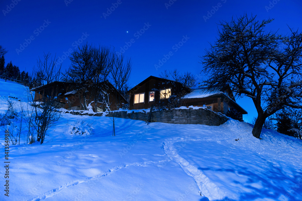 Wooden house in snow at winter night