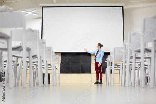 Young student pointing at blank whiteboard