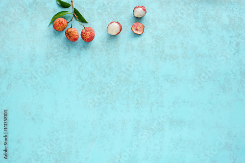 Bunch of fresh lychee (litchi, liche) on a blue background. Space for text. Top view.