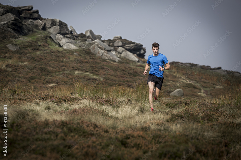 Male runner running down from Stanage Edge, Peak District, Derbyshire, UK Male runner running down from Stanage Edge, Peak District, Derbyshire, UK