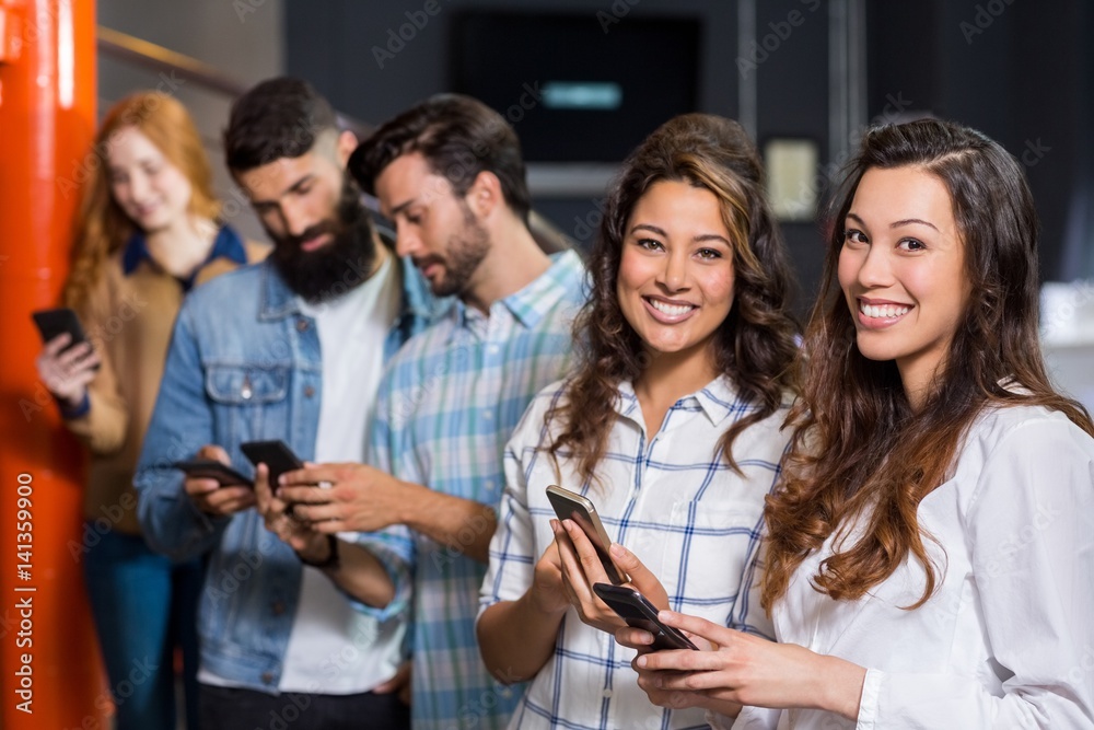 Obraz premium Happy male and female executive using mobile phone in office