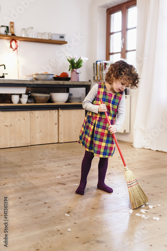 Cute girl sweeping kitchen floor