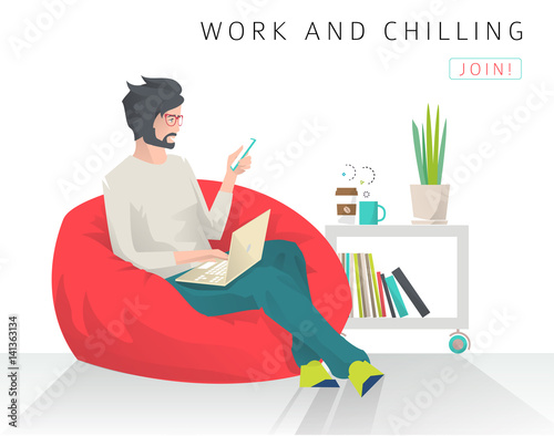 Young man sits on bean bag with different gudgets.