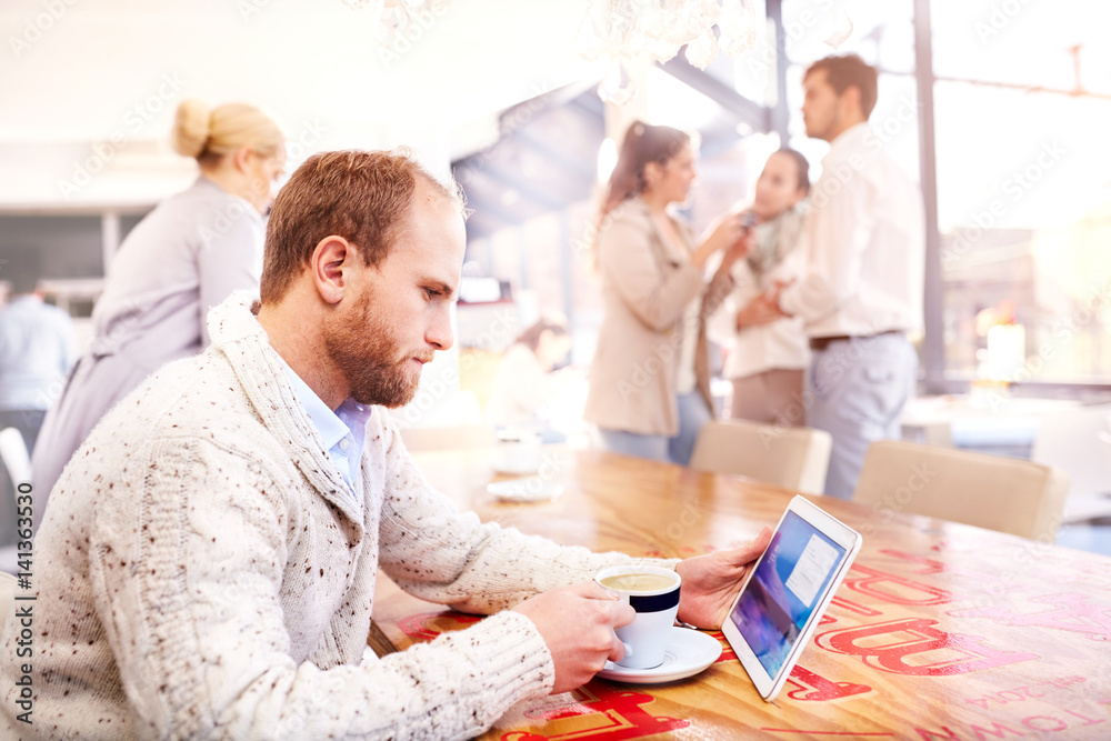 Young man alone in cafe looking at digital tablet Young man alone in cafe looking at digital tablet