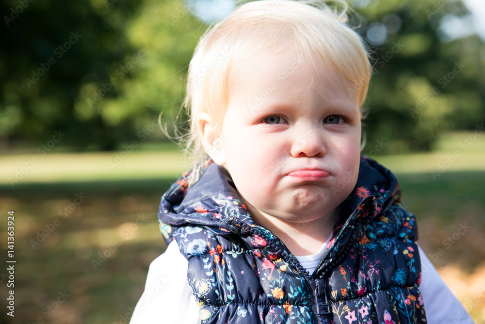 Portrait of female toddler with sulking lip in park