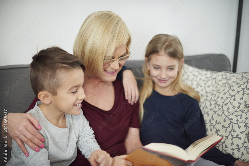 Grandmother and grandchildren reading book on sofa Grandmother and grandchildren reading book on sofa