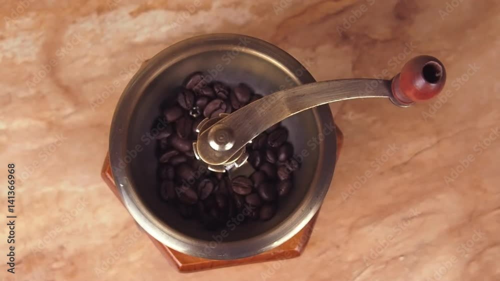 A coffee mill filled with coffee beans. Coffee grinder with coffee beans. In the kitchen on the marble table. A coffee mill filled with coffee beans. Coffee grinder with coffee beans. In the kitchen on the marble table.