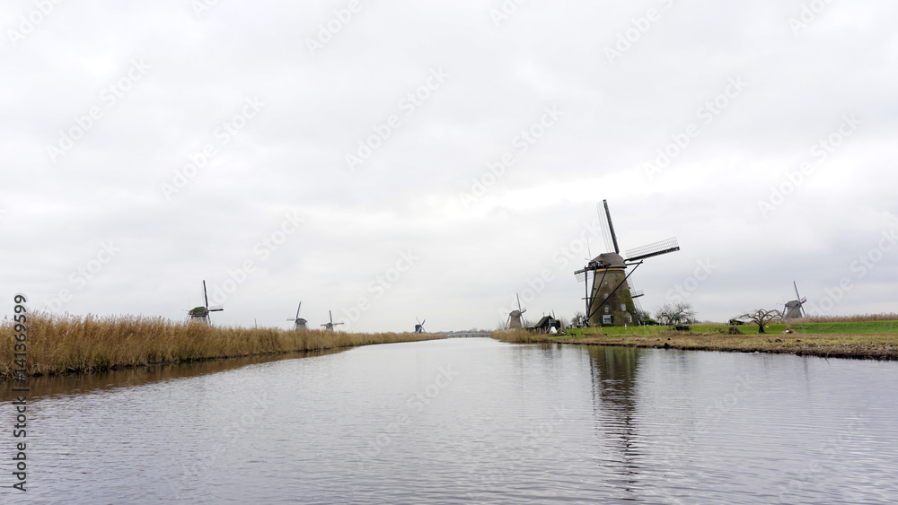 Windmills in landscape view with smooth river surface