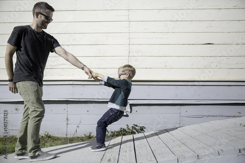 Boy pulling father up wooden ramp