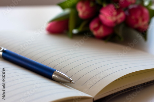 Tulips, pen and notebook on white cover