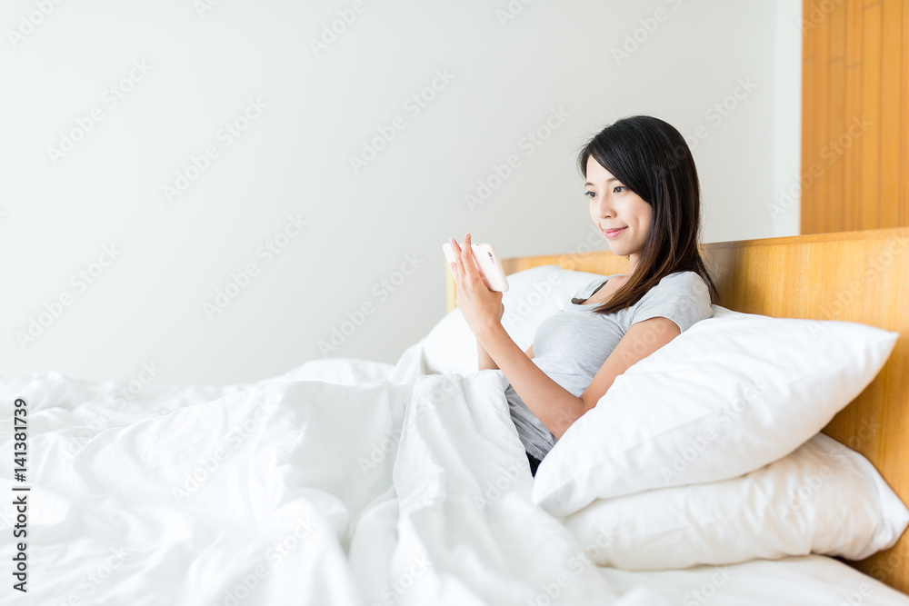 Woman watcing on mobile phone and lying on bed Woman watcing on mobile phone and lying on bed