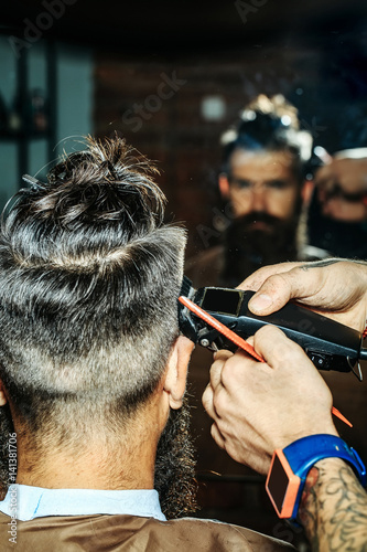 Bearded man with beard getting haircut by hairdresser at barbershop