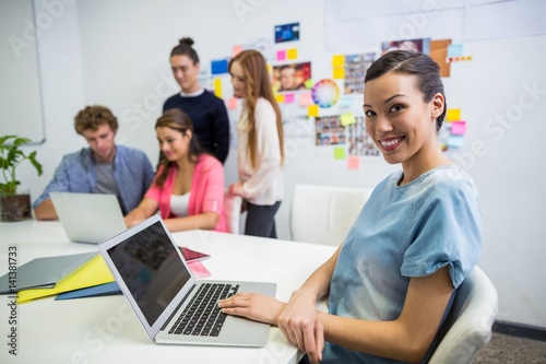 Smiling executive working on laptop in office