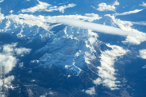 Idyllic snowy mountain peaks under clouds from plane