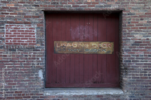 Rustic, abandoned loading dock door surrounded by aging brick wall.