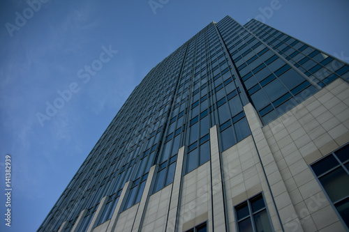Tall concrete  glass and steel building climbing into a clear blue sky. Unique perspective. Plenty of room for text.
