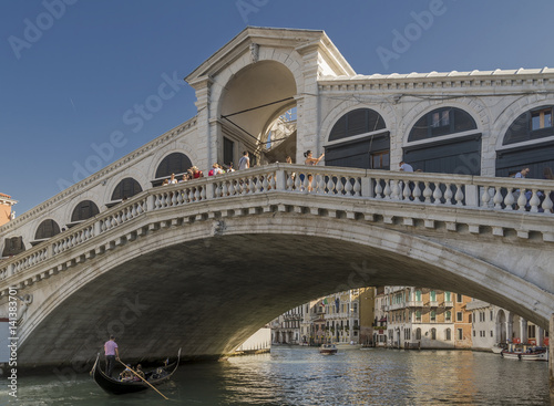 A gondola passes under the Rialto Bridge of Venice, Italy