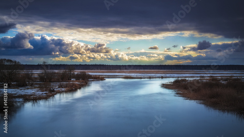 A river with dark clouds and a clearing in the distance