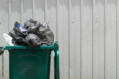 Green garbage bin with black garbage bags. photo