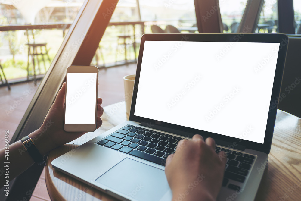 Mockup image of a hand on laptop with blank white screen on wooden ...