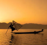 Fisherman silhouette at sunset during evening fishing on Inle lake, Myanmar