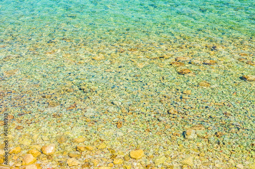 Kamienie w wodzie. Kamienista plaża. Kolorowe refleksy na wodzie.