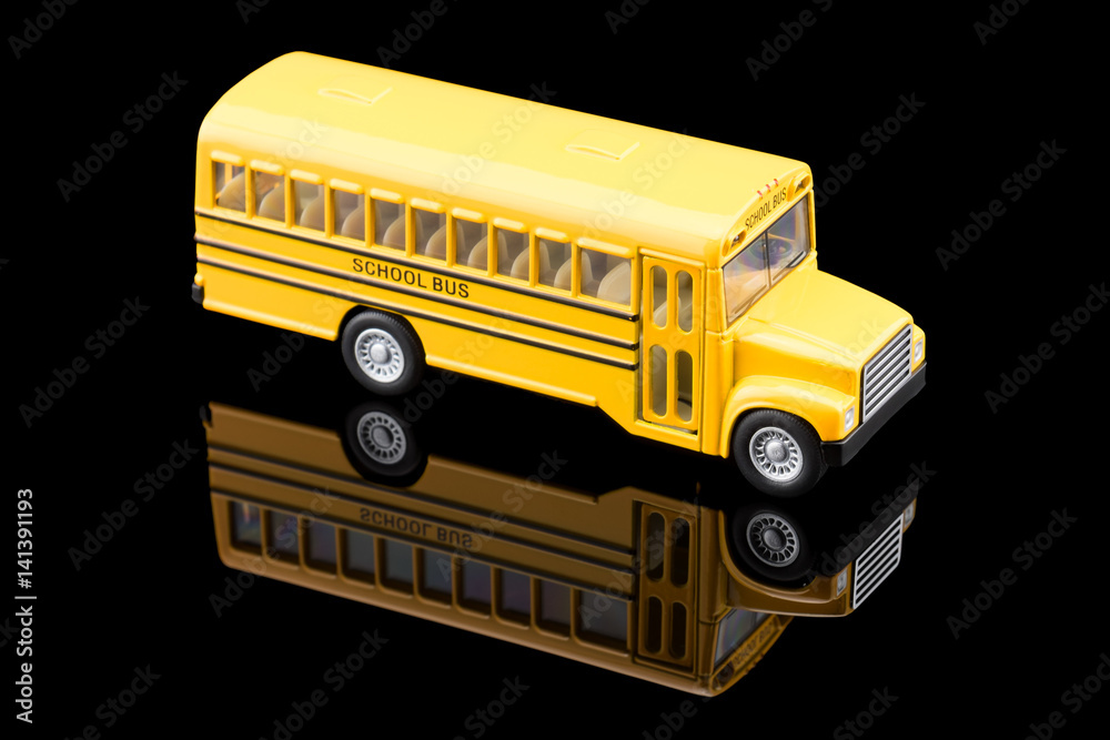 Toy School Bus with reflection on on black background.