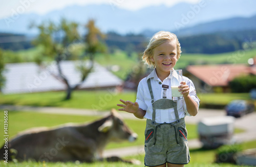 Fotografie Happy bavarian boy drinking milk on the farm in Germany .