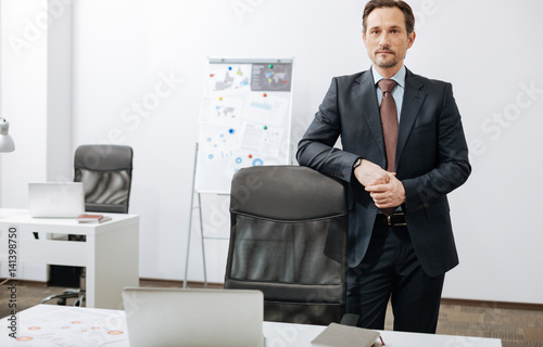 Pleasant aged businessman standing in the office