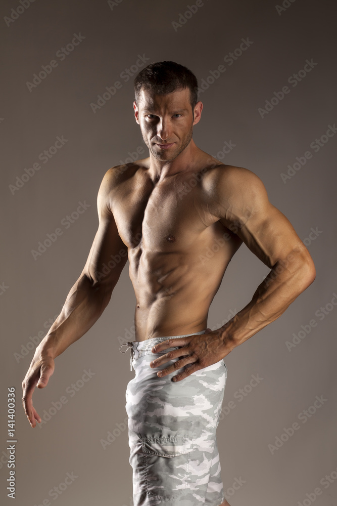 Fototapeta premium half-naked handsome and muscular young man posing on a gray background