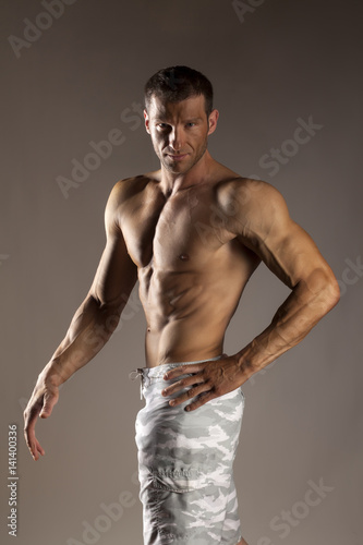 half-naked handsome and muscular young man posing on a gray background