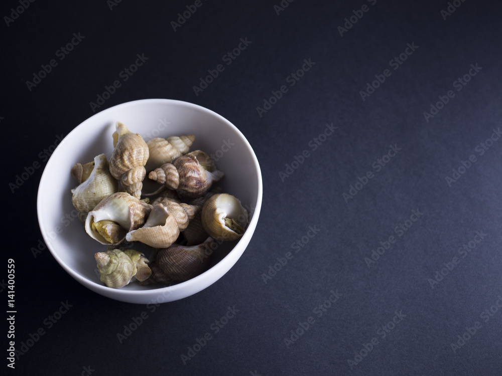 Whelks, sea snails, in white bowl isolated on black background Whelks, sea snails, in white bowl isolated on black background