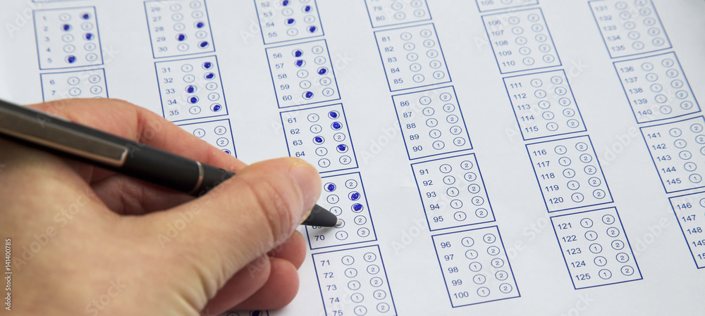 Filling exam questionnaire,hand with pen marking right answers at school or university Filling exam questionnaire,hand with pen marking right answers at school or university