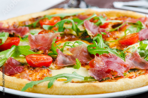 Tasty Italian Pizza With Prosciutto, Fresh Tomatoes And Rucola Closeup