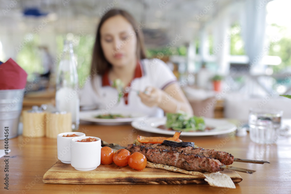 Woman having lunch in summer restaurant blurred background