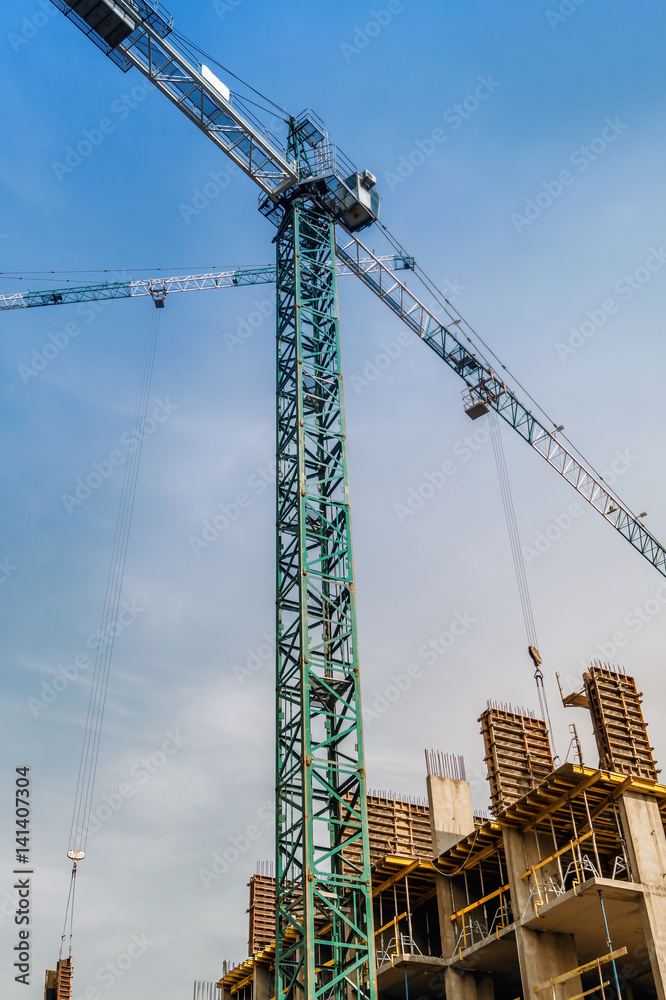 Construction crane above buildings against the blue sky