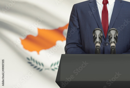 Businessman or politician making speech from behind a pulpit with national flag on background - Cyprus