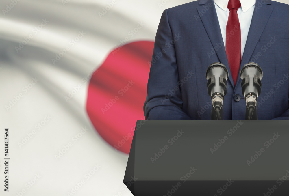 Fototapeta premium Businessman or politician making speech from behind a pulpit with national flag on background - Japan