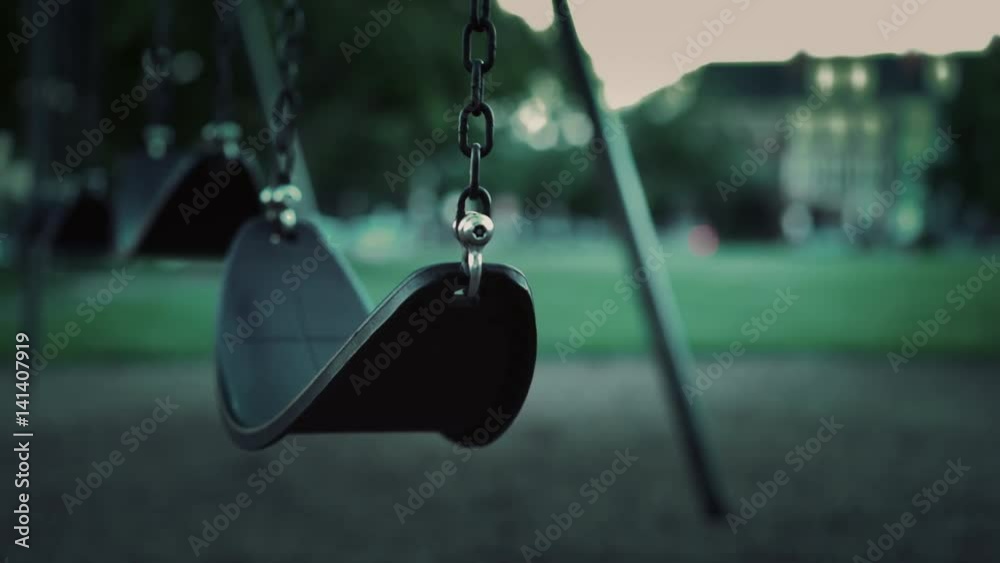 Empty swing in park during evening hours with no children.
