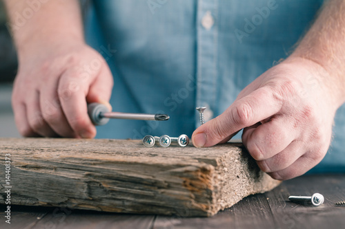 screws on wood in male hands