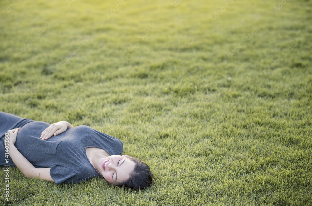 Pregnant Asian women lying on grass with copyspace Pregnant Asian women lying on grass with copyspace