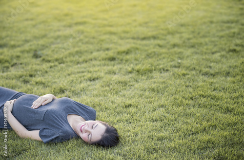 Pregnant Asian women lying on grass with copyspace © jaengpeng