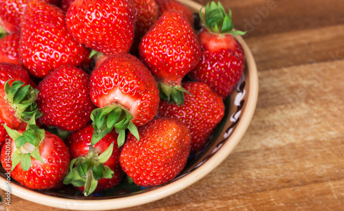 Fresh ripe strawberries in plate on a wooden background